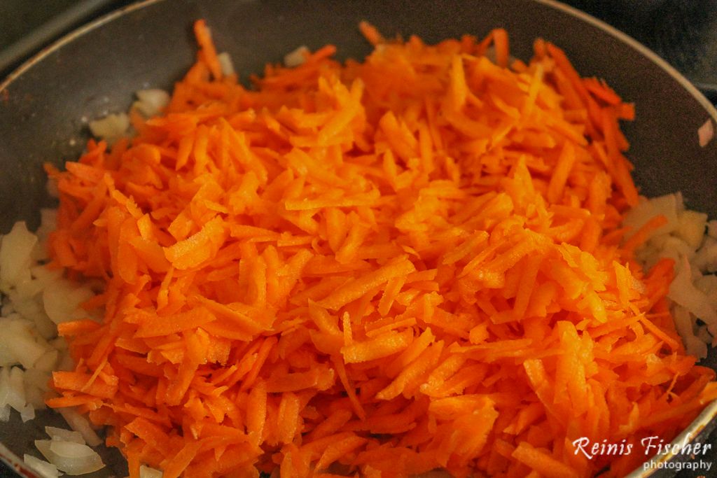 Chopped onions and grated carrots on pan